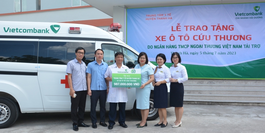Bà Hoàng Thị Kim Ngân - Phó Giám đốc Vietcombank Hải Dương (đứng thứ 3 từ trái sang) trao biển tài trợ xe ô tô cứu thương cho lãnh đạo Trung tâm y tế huyện Thanh Hà