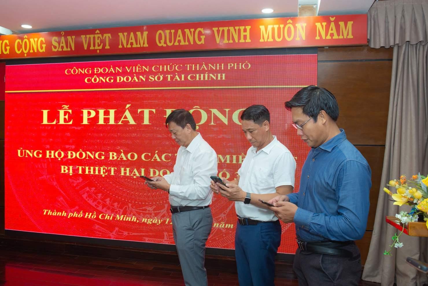 Ông Nguyễn Hoàng Hải - Giám đốc Sở Tài chính TP. Hồ Chí Minh (bìa trái) và đoàn viên công đoàn thực hiện chuyển khoản ủng hộ tại buổi lễ. Ảnh: Văn Quý