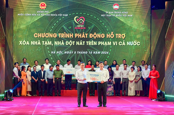 Ông Nguyễn Thanh Tùng (bên trái) - Bí thư Đảng uỷ, Chủ tịch HĐQT Vietcombank trao bảng tượng trưng kinh phí 100 tỷ đồng hỗ trợ xoá nhà tạm, nhà dột nát ủng hộ cho đại diện địa phương