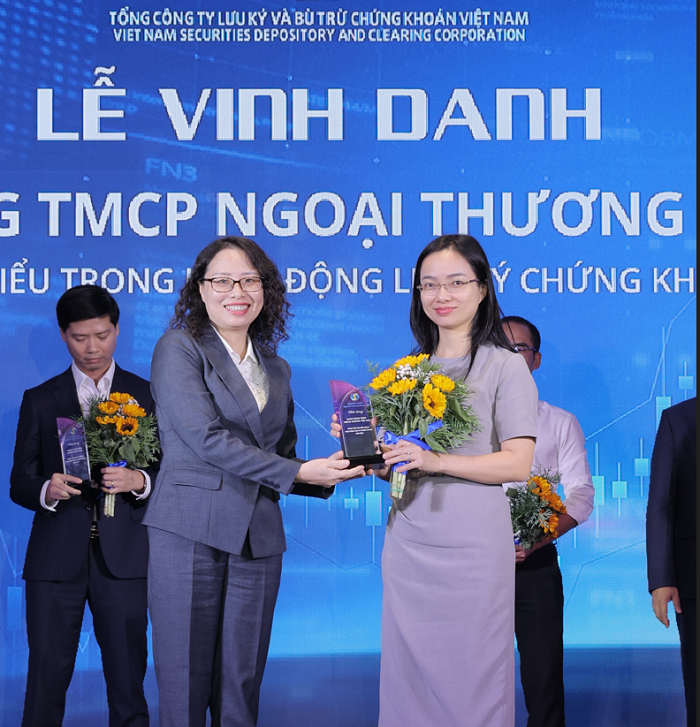 Bà Tạ Thanh Bình - Tổng Giám đốc VSDC (bên trái) trao tặng hoa và kỷ niệm chương cho đại diện Vietcombank - ngân hàng tiêu biểu trong hoạt động lưu ký chứng khoán năm 2024