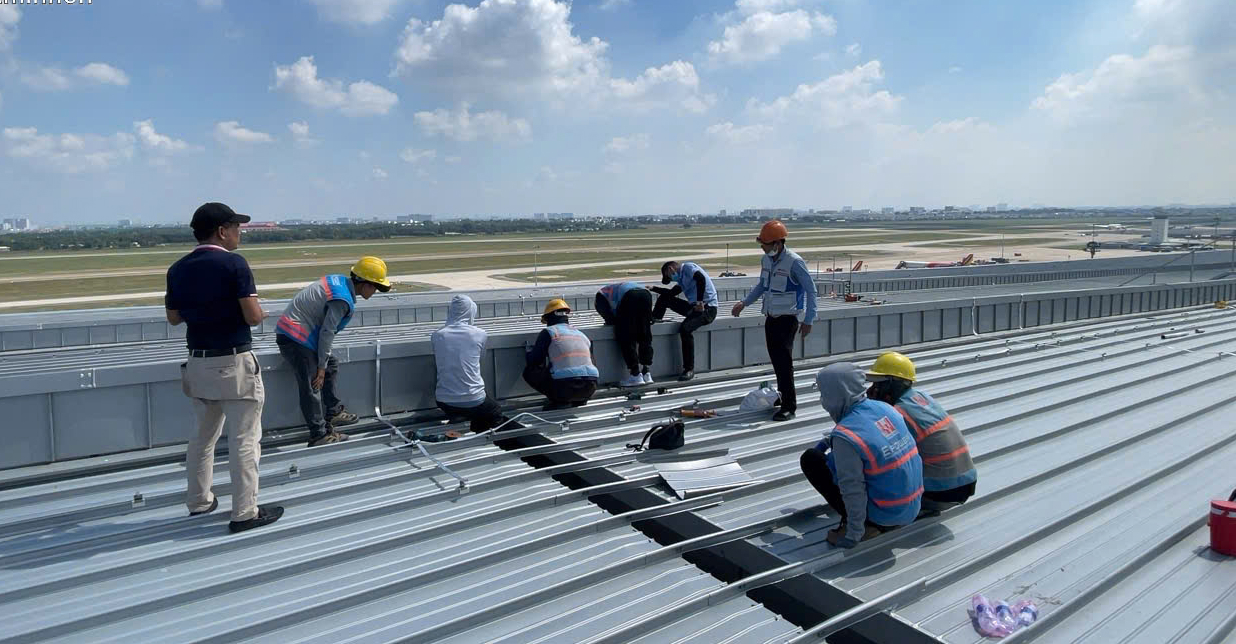 Công nhân bơm keo để khắc phục sự cố keo co ngót làm hở mái chính và mái lấy sáng. Ảnh: Quân Chính