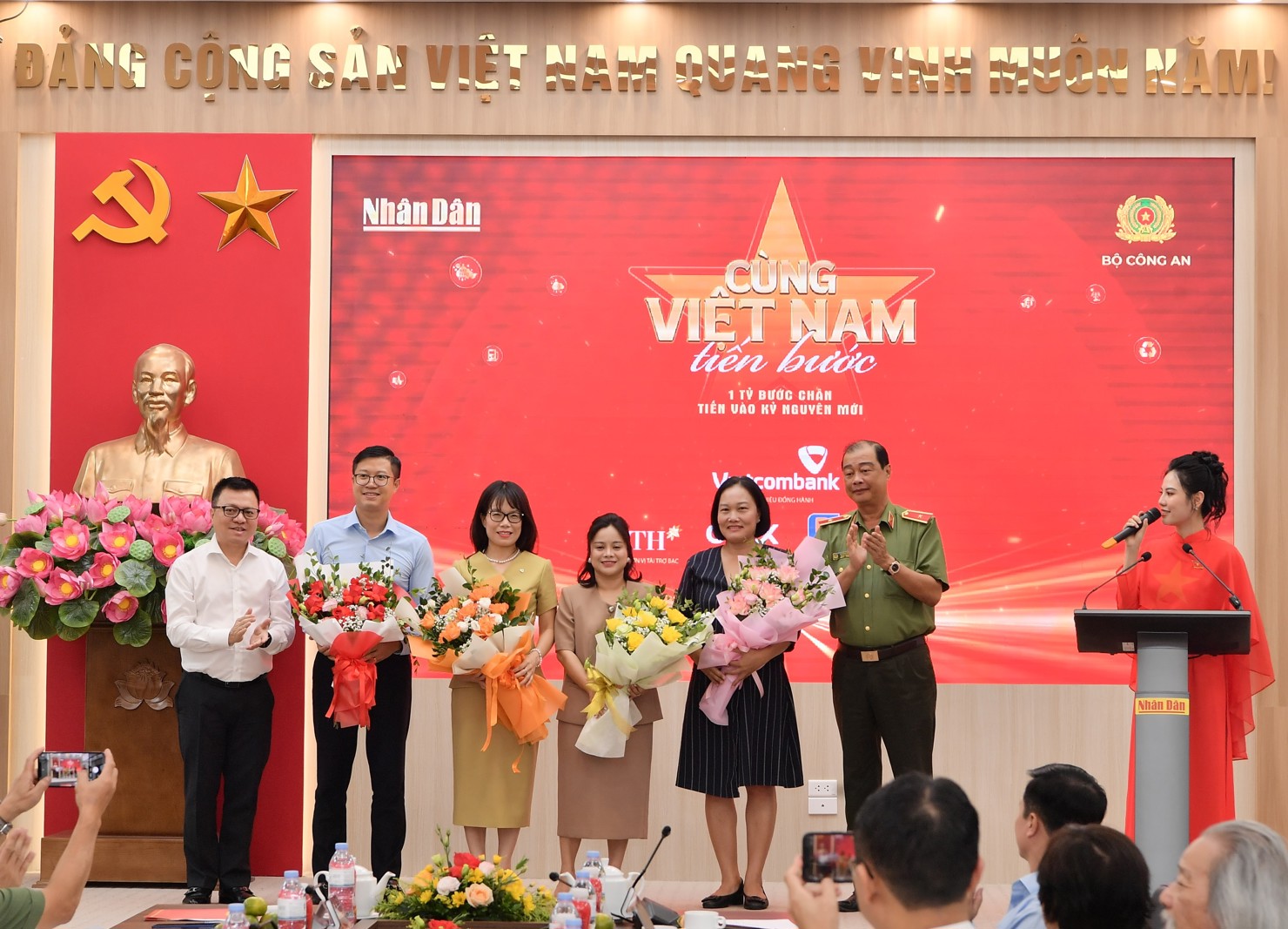Đồng chí Lê Quốc Minh - Ủy viên BCH Trung ương Đảng, Tổng Biên tập Báo Nhân Dân, Phó Trưởng Ban Tuyên giáo và Dân vận Trung ương, Chủ tịch Hội Nhà báo Việt Nam (bên trái) và Thiếu tướng Lê Hồng Hiệp - Phó Cục trưởng Cục Công tác chính trị Bộ Công an (bên phải) tặng hoa cho đại diện thương hiệu đồng hành Vietcombank - bà Đoàn Hồng Nhung, Thành viên Ban Điều hành, Giám đốc Khối Bán lẻ (thứ 3 từ trái sang) cùng các nhà tài trợ khác.