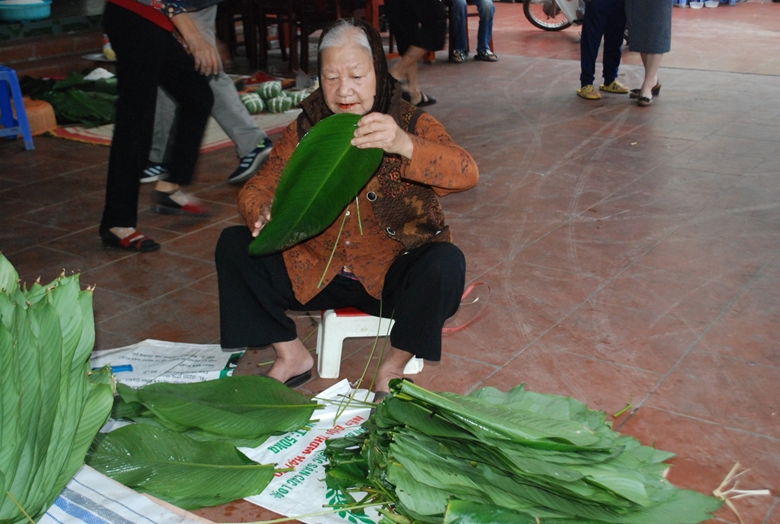 Cụ Nguyễn Thị Thuận (hơn 80 tuổi) đang tước l&aacute; dong phụ gia đ&igrave;nh l&agrave;m b&aacute;nh.