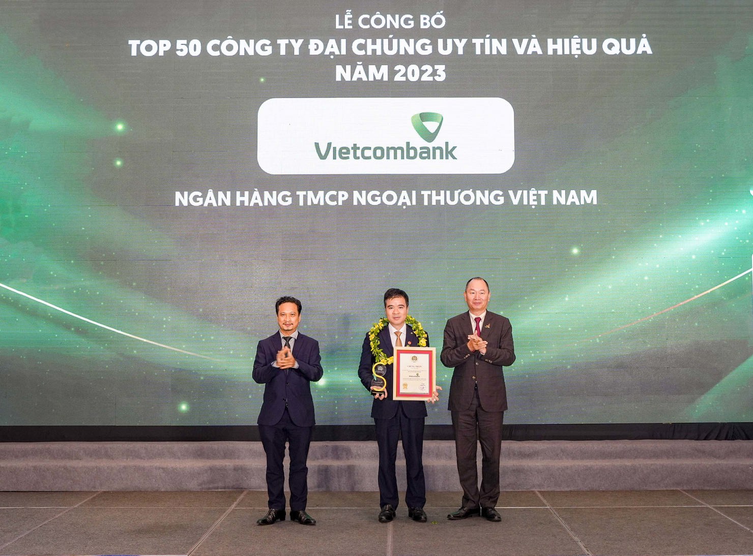 Đại diện Vietcombank (đứng giữa) nhận danh hiệu &ldquo;C&ocirc;ng ty đại ch&uacute;ng uy t&iacute;n v&agrave; hiệu quả nhất Việt Nam năm 2023&rdquo; từ Ban Tổ chức.