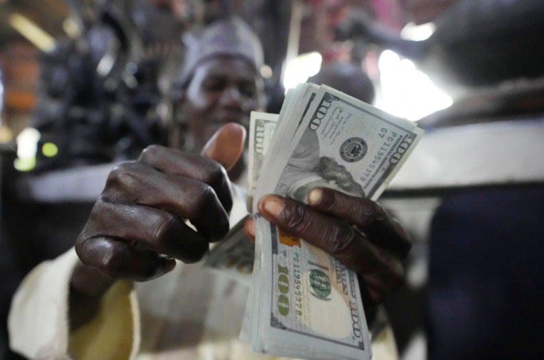 Một người Nigeria đang đếm những đồng đôla ở khu chợ thủ công Lagos, Nigeria. Ảnh: AP