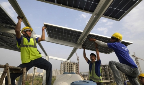 Các công nhân lắp đặt một tấm pin mặt trời trên sân thượng ở ngoại ô New Delhi, Ấn Độ vào ngày 20/2. Ảnh: AP