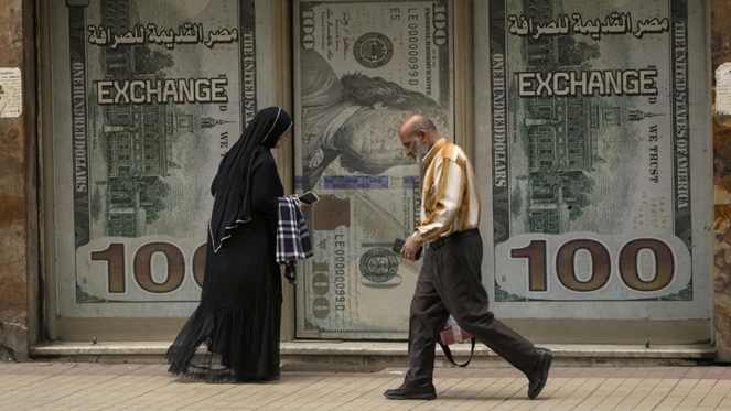 Người dân Ai Cập đi qua một văn phòng trao đổi ngoại tệ ở Cairo. Ảnh: AP
