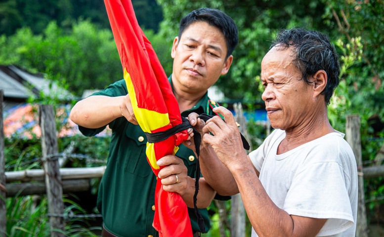 Bộ đội bi&ecirc;n ph&ograve;ng hướng dẫn người d&acirc;n bản Y&ecirc;n Hợp (x&atilde; Thượng H&oacute;a, huyện Minh H&oacute;a) treo cờ rủ - Ảnh: VGP/LH