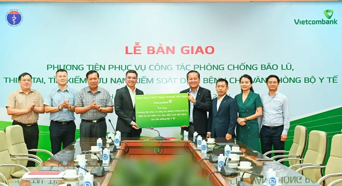 Đại diện Vietcombank l&agrave; &ocirc;ng Nguyễn Việt Cường - Ph&oacute; Tổng Gi&aacute;m đốc (thứ 4 từ phải sang) v&agrave; đại diện Bộ Y tế l&agrave; &ocirc;ng H&agrave; Anh Đức - Ch&aacute;nh Văn ph&ograve;ng Bộ Y tế (thứ 4 từ tr&aacute;i sang) thực hiện nghi thức trao g&oacute;i an sinh x&atilde; hội