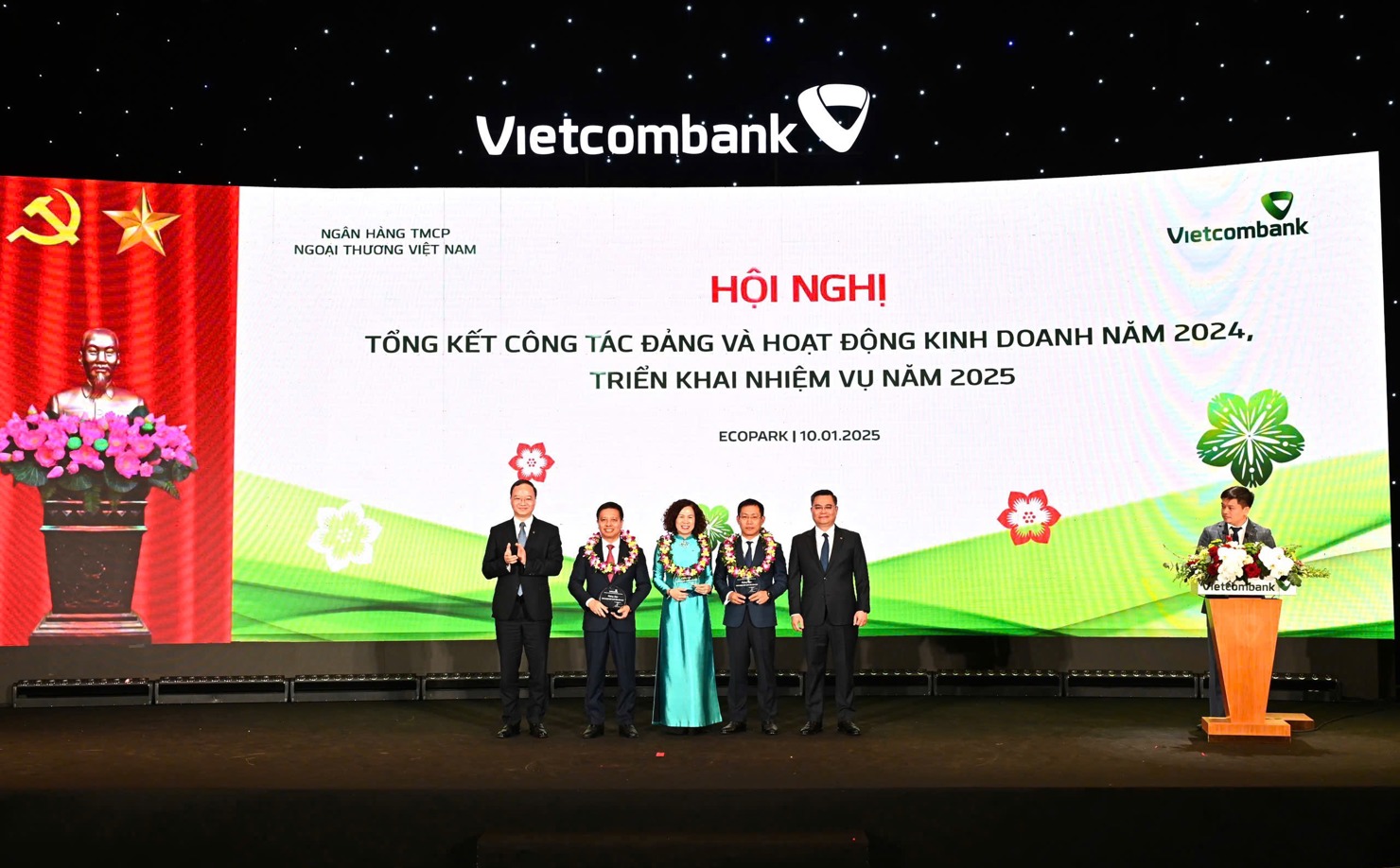 Ban l&atilde;nh đạo Vietcombank trao biểu trưng v&agrave; tặng hoa vinh danh cho đại diện 03 Đơn vị đặc biệt xuất sắc trong năm 2024: Chi nh&aacute;nh Sở Giao dịch (thứ 4 từ tr&aacute;i sang), Chi nh&aacute;nh Th&agrave;nh C&ocirc;ng (thứ 3 từ tr&aacute;i sang) v&agrave; Chi nh&aacute;nh Nam S&agrave;i G&ograve;n (thứ 2 từ tr&aacute;i sang).