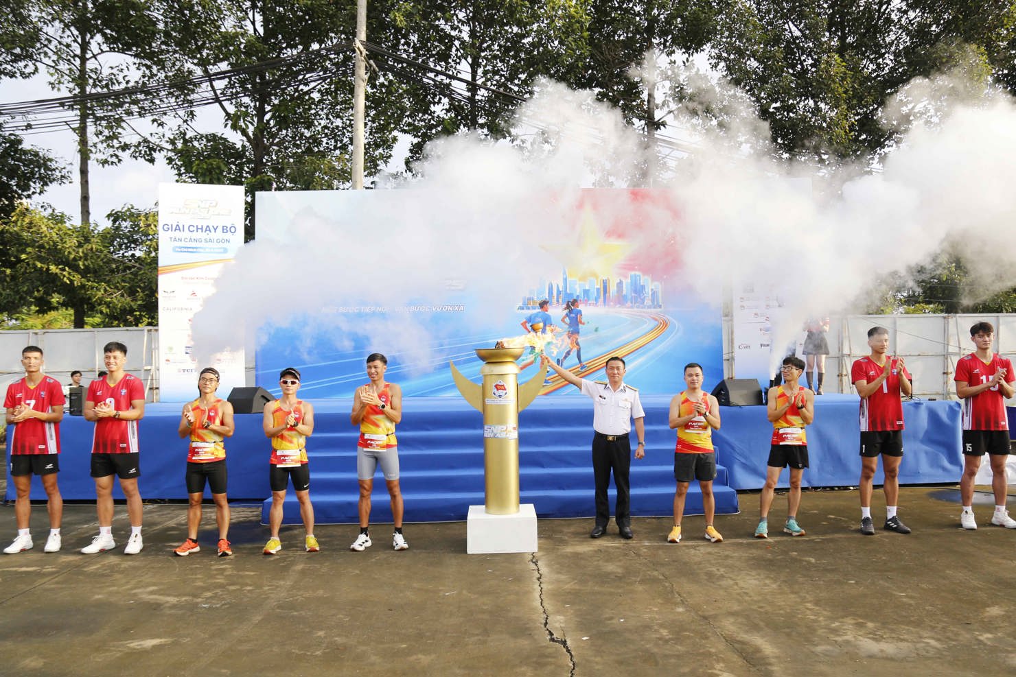 Đại tá Bùi Văn Quỳ và các cầu thủ đội bóng chuyền Thể Công - Tân Cảng châm đuốc khai mạc giải chạy. 