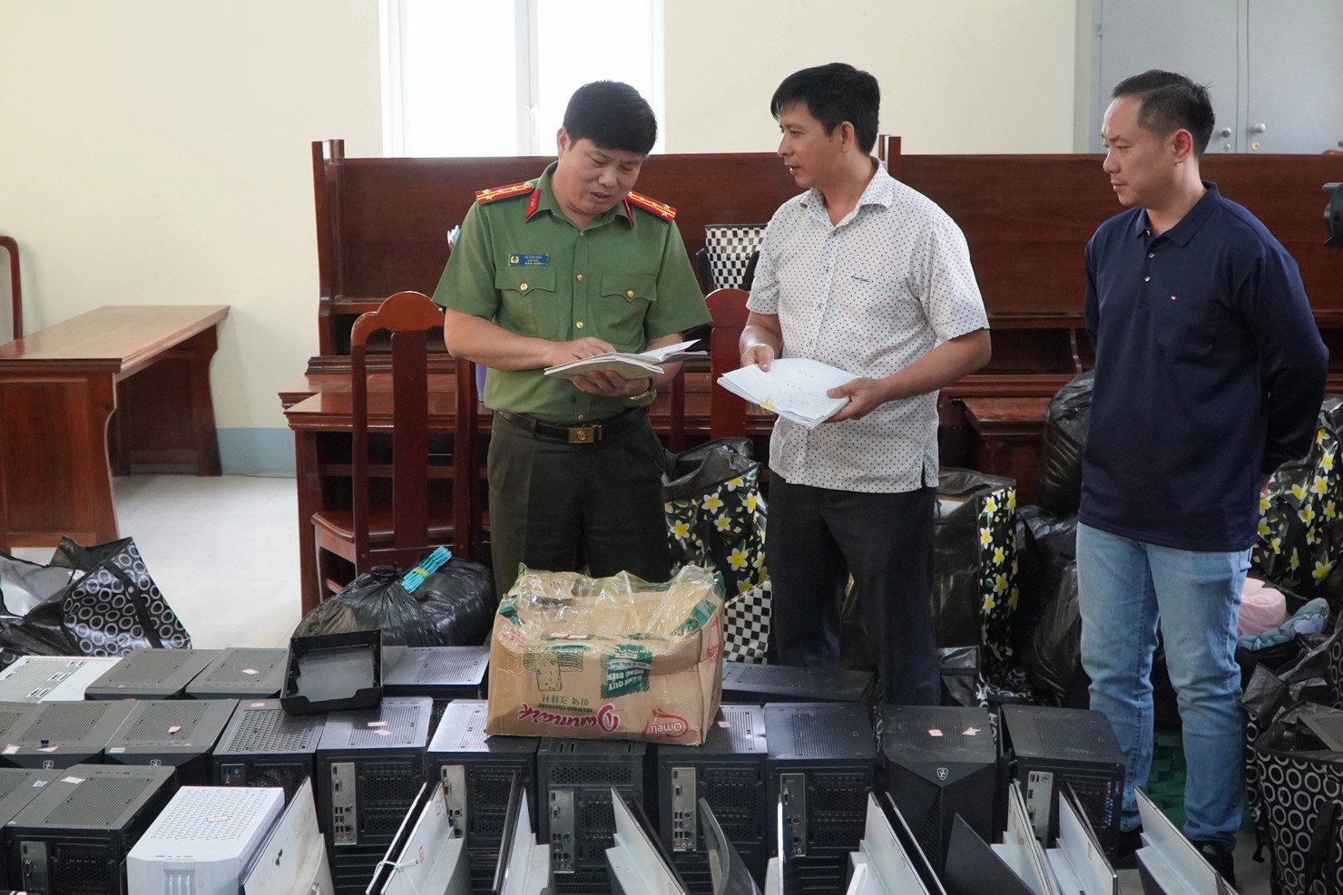 Đại tá Vũ Văn Đấu - Giám đốc Công an tỉnh Điện Biên kiểm tra tang vật và kịch bản lừa đảo của các đối tượng trong Chuyên án 625T. Ảnh: Công an cung cấp.