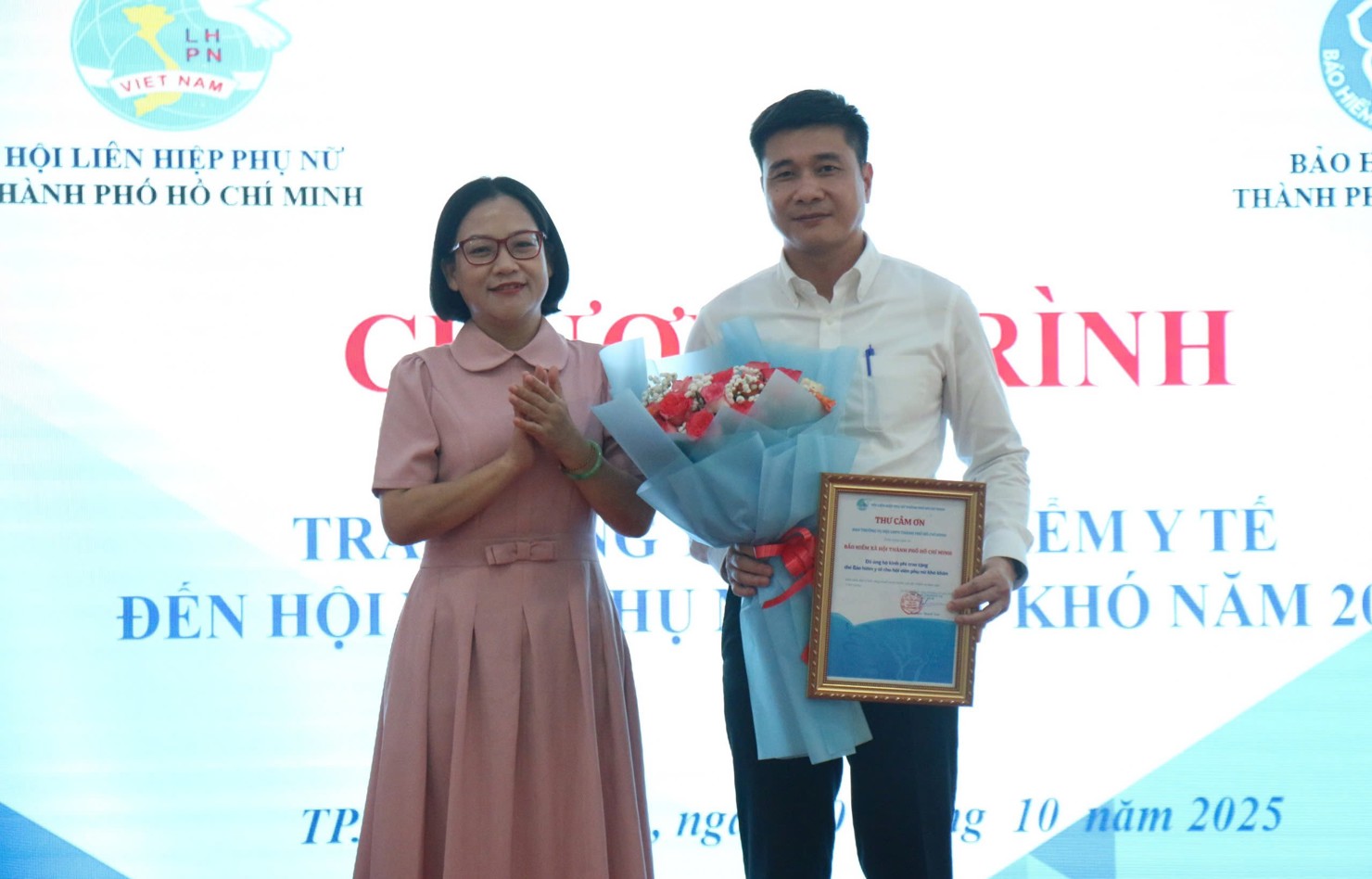 &Ocirc;ng Trần Dũng H&agrave; nhận thư cảm ơn v&agrave; hoa của đại diện Hội LHPN Th&agrave;nh phố về việc cơ quan BHXH TP. HCM đ&atilde; hỗ trợ 304 thẻ BHYT cho hội vi&ecirc;n phụ nữ kh&oacute; khăn. Ảnh: PT