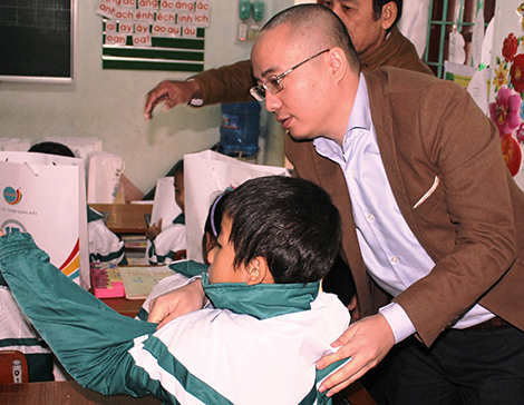 Ông Nguyễn Phan Huy Khôi, Giám đốc Đối ngoại, Tập đoàn Number 1 đang mặc áo ấm cho một em nhỏ dân tộc Vân Kiều trong dịp đi cùng đoàn. Ảnh THP