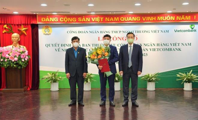 Ông Trần Hồng Tuấn – Phó Chủ tịch Công đoàn NHVN (bên trái) trao Quyết định và ông Phạm Quang Dũng- Chủ tịch HĐQT Vietcombank (bên phải) tặng hoa ông Hồng Quang - Thành viên HĐQT kiêm Giám đốc Khối Nhân sự - tân Chủ tịch Công đoàn Vietcombank