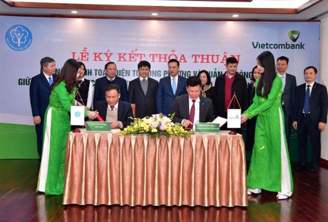 Ông Phạm Mạnh Thắng–Phó Tổng Giám đốc Vietcombank (ngồi bên phải) và ông Lê Hùng Sơn–Phó Tổng Giám đốc BHXH Việt Nam (ngồi bên trái) ký kết Thỏa thuận