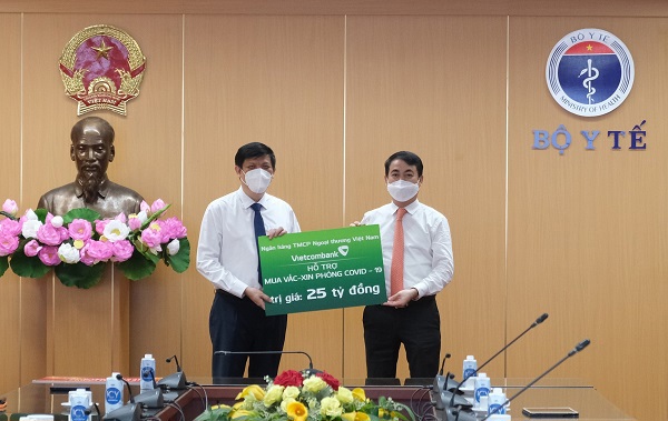 Ông Nghiêm Xuân Thành - Chủ tịch HĐQT Vietcombank (bên phải) trao biển tượng trưng số tiền 25 tỷ đồng hỗ trợ Bộ Y tế mua vắc xin phòng Covid-19 cho Bộ trưởng Bộ Y tế Nguyễn Thanh Long