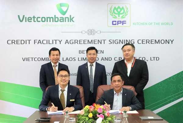 Ông Wiley Khotnhotha - Phó Tổng Giám đốc Vietcombank Lào (hàng đầu, bên trái) và ông Thamnong Pholthongmak - Chủ tịch CP Lào ký kết trước sự chứng kiến của đại diện lãnh đạo hai bên