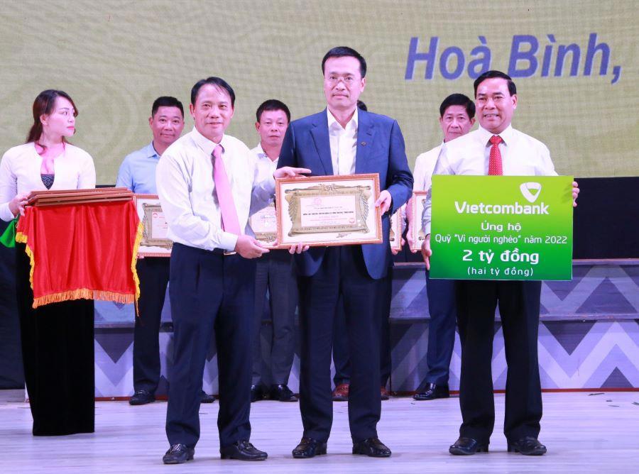 Ông Phạm Quang Dũng - Chủ tịch HĐQT Vietcombank (đứng giữa) trao ủng hộ 2 tỷ đồng của Vietcombank cho Quỹ “Vì người nghèo” tỉnh Hòa Bình và nhận chứng nhận ủng hộ từ Ban Tổ chức