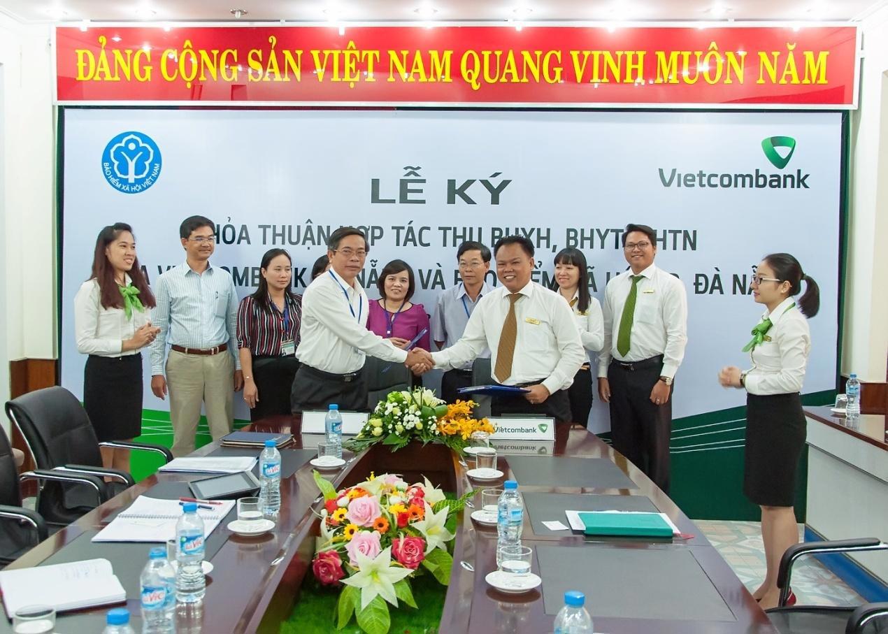 Ông Đinh Văn Hiệp - Giám đốc BHXH T.P Đà Nẵng (hàng đầu bên trái) và ông Nguyễn Hữu Đức - Phó Giám đốc Vietcombank Đà Nẵng (hàng đầu bên phải) đại diện hai bên tiến hành ký kết thỏa thuận.