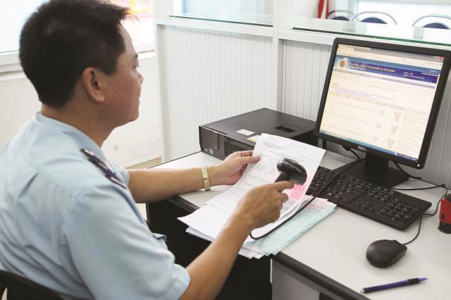 Công chức hải quan giám sát sử dụng thiết bị mã vạch để kiểm tra thông tin tờ khai hải quan