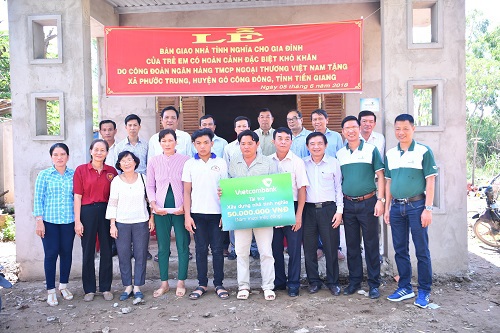 Gia đình ông Huỳnh Văn Được cùng đại diện Vietcombank và lãnh đạo địa phương chụp ảnh lưu niệm bên ngôi nhà mới