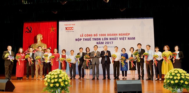 Bà Phùng Nguyễn Hải Yến – Phó Tổng giám đốc Vietcombank (thứ 10 từ trái sang) nhận Kỷ niệm chương và hoa của Ban Tổ chức vinh danh Vietcombank là ngân hàng nộp thuế thu nhập lớn nhất Việt Nam