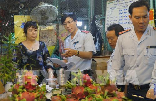Cán bộ Ban Quản lý an toàn thực phẩm Thành phố Hồ Chí Minh kiểm tra trái cây, hóa đơn mua bán tại Chợ nông sản Thủ Đức.