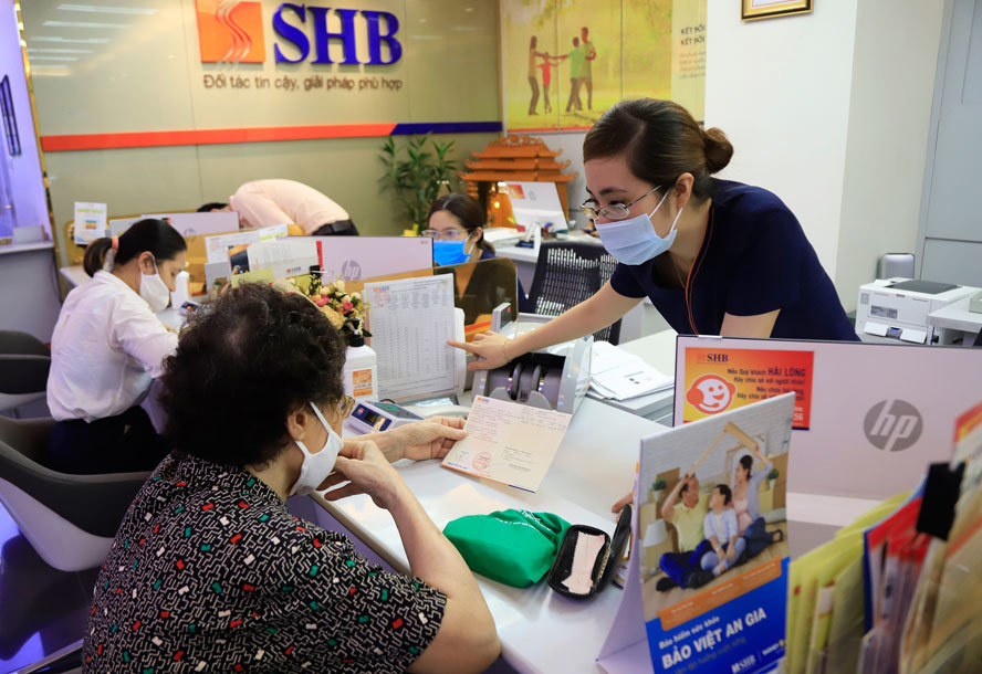 Nhân viên Ngân hàng Thương mại cổ phần Sài Gòn - Hà Nội (SHB) tư vấn cho người cao tuổi về các dịch vụ ngân hàng trực tuyến. Ảnh: Quang Thái