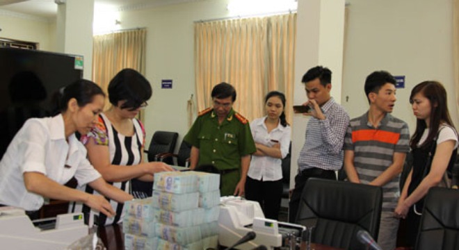 Cơ quan công an phối hợp với cán bộ ngân hàng kiểm tra tiền thu được tại Công ty Khải Thái. Nguồn: ktdt.com.vn