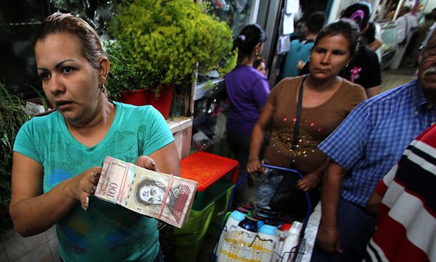 Một phụ nữ cầm một tệp tiền 100 bolivar ở San Cristobal, Venezuela. Ảnh: AFP