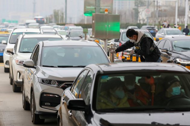 Nhân viên phòng dịch đo thân nhiệt của người ngồi trên ô tô tại Trung Quốc. Trong ảnh, tất cả người trong xe đều đeo khẩu trang. Ảnh: Reuters