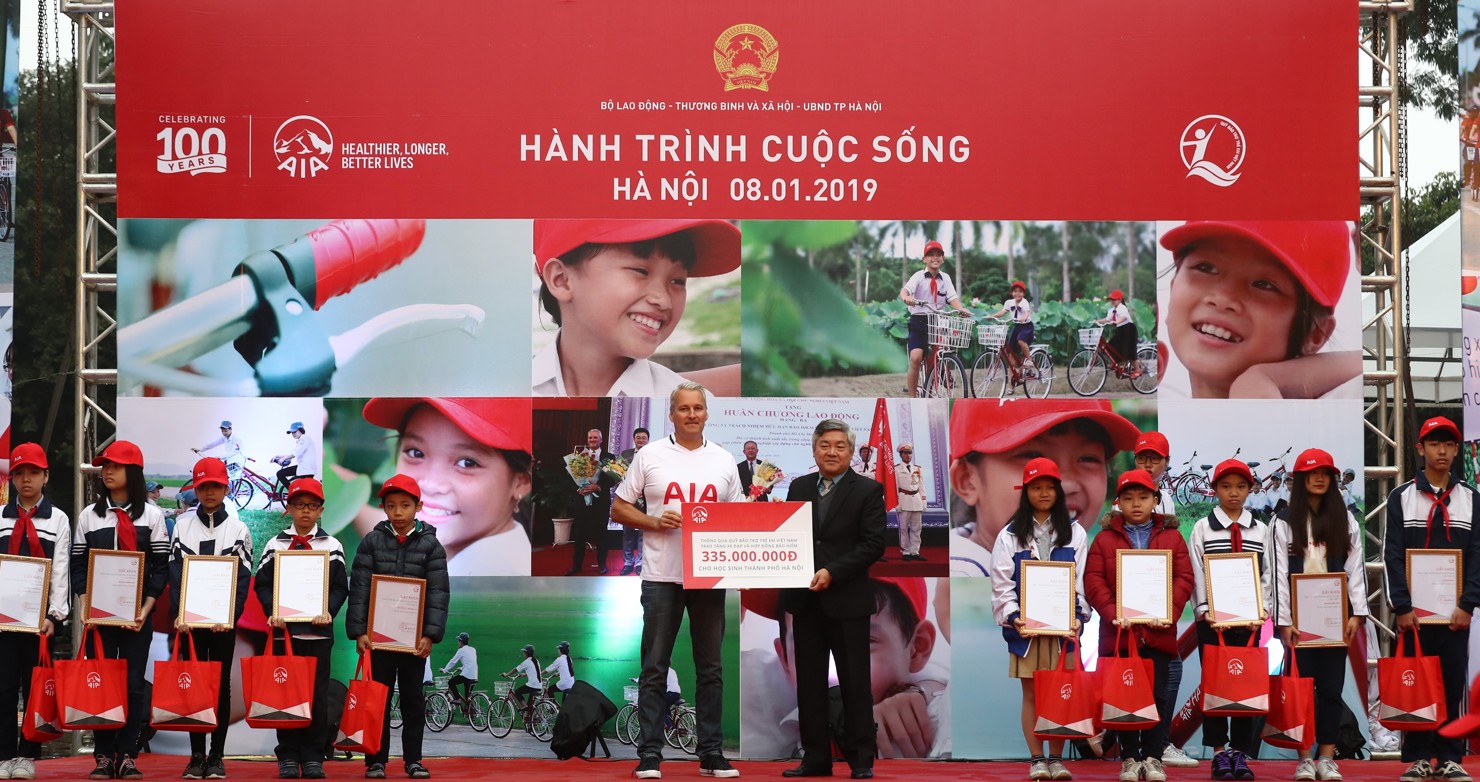 Ông Wayne Besant, Tổng Giám đốc AIA Việt Nam trao tặng 100 chiếc xe đạp, và quà, 5 hợp đồng bảo hiểm nhân thọ miễn phí cho 105 em học sinh có hoàn cảnh khó khăn của TP. Hà Nội. 