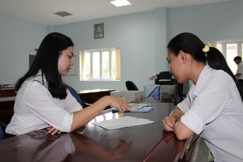 Cán bộ Chi cục Thuế huyện Cần Giờ, TP. Hồ Chí Minh (trái) phổ biến chính sách thuế mới cho người nộp thuế. Ảnh: NM.