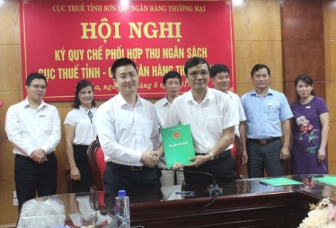 Ông Nguyễn Quang Việt (hàng trên bên phải) Cục trưởng Cục Thuế Sơn La và đại diện các ngân hàng thương mại ký quy chế phối hợp thu ngân sách. Ảnh: Thu Mây