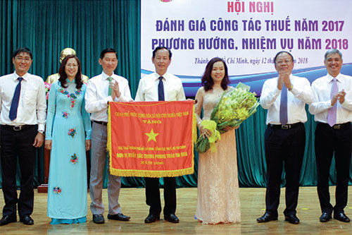 Thừa ủy quyền của Thủ tướng Chính phủ, Tổng cục trưởng Tổng cục Thuế Bùi Văn Nam (thứ 2 từ bên phải) trao Cờ thi đua của Chính phủ cho Cục Thuế TP. Hồ Chí Minh.