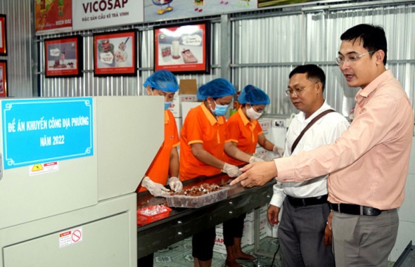Ông Trần Duy Linh (phải), Giám đốc Công ty TNHH chế biến dừa sáp Cầu Kè giới thiệu về máy đóng gói kẹo viên. Ảnh: Trường Nguyên