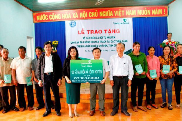 Bà Đỗ Thị Việt Hằng - Giám đốc Vietcombank Gia Lai trao tặng 100 sổ Bảo hiểm xã hội cho các cán bộ không chuyên trách thôn làng trước  sự chứng kiến của đại diện lãnh đạo địa phương